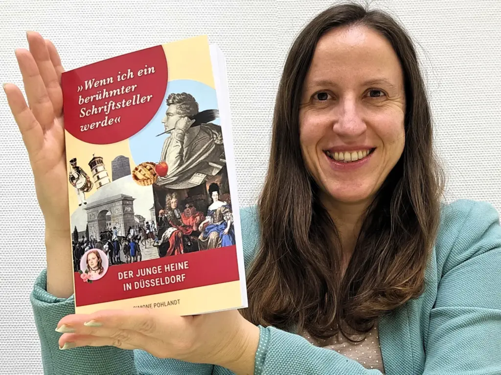 Autorin Simone Pohlandt hält ihr Buch „Wenn ich ein berühmter Schriftsteller werde – Der junge Heine in Düsseldorf" in den Händen